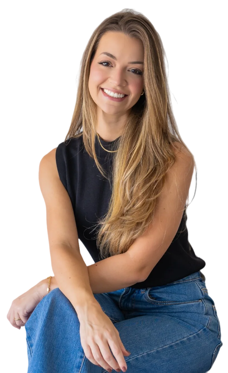 Dra. Letícia Fitipaldi sentada, sorrindo, de regata preta e calça jeans